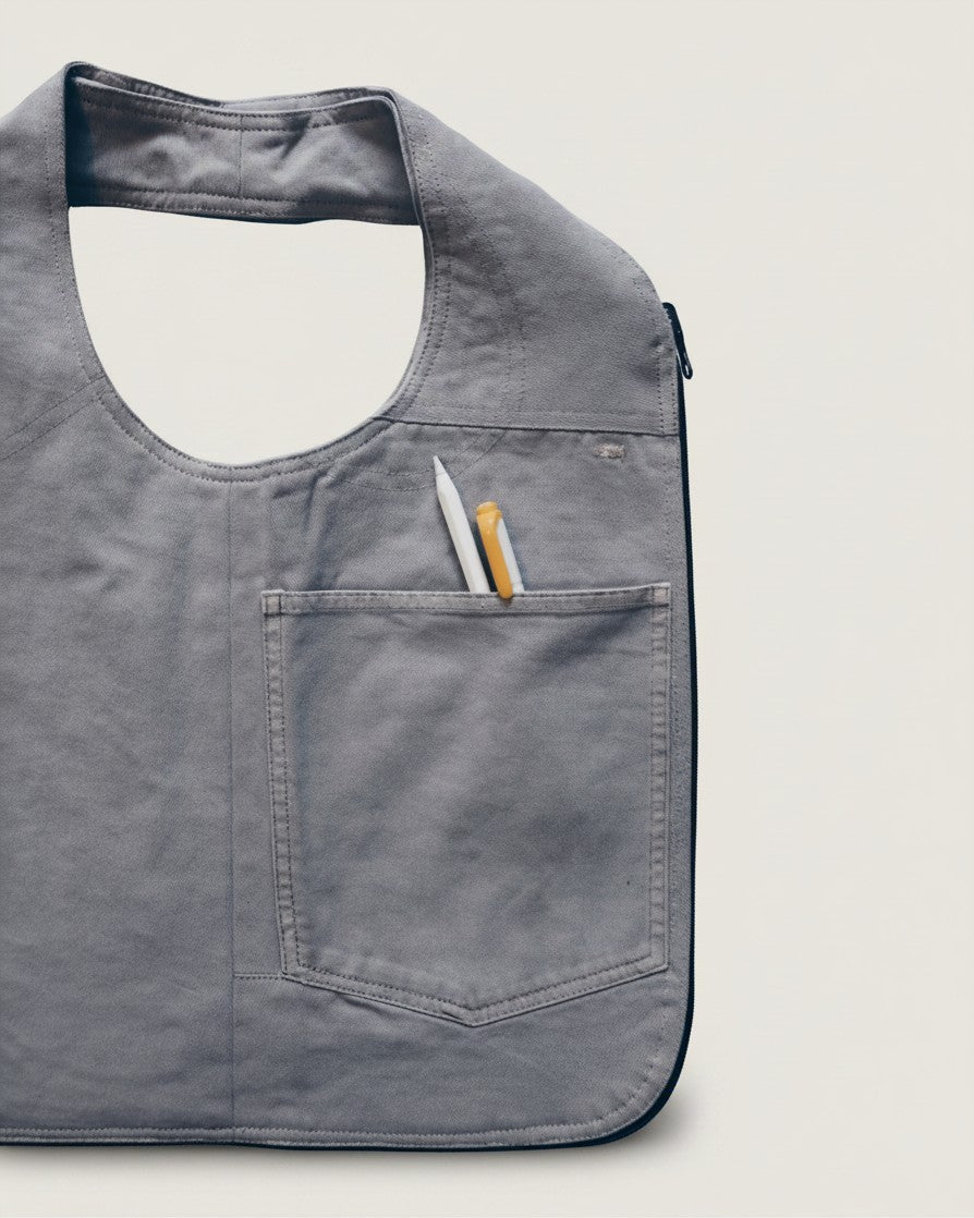 Hue Labs Ash Vest Bag in grey upcycled fabric with a front pocket holding pens, featuring a versatile reversible design