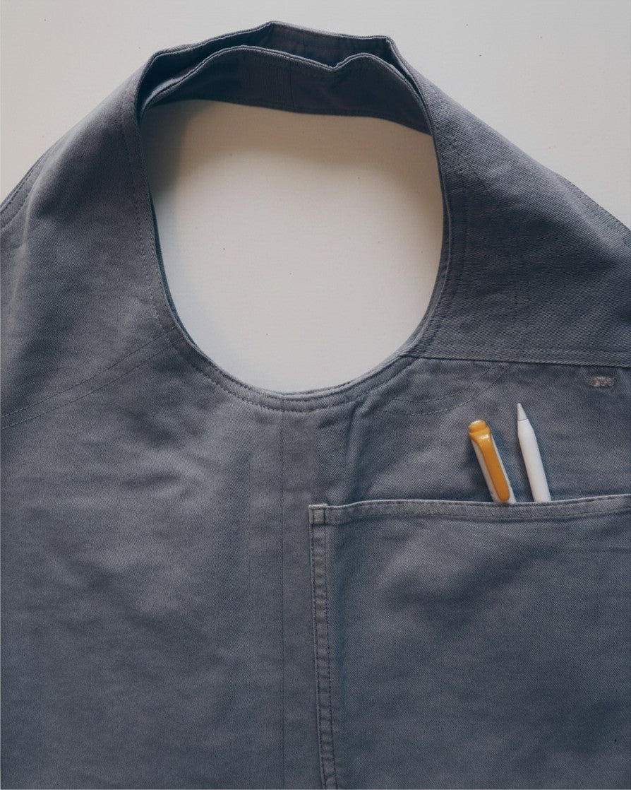 Hue Labs Ash Vest Bag in grey upcycled fabric with a front pocket holding two pens, featuring a versatile design.