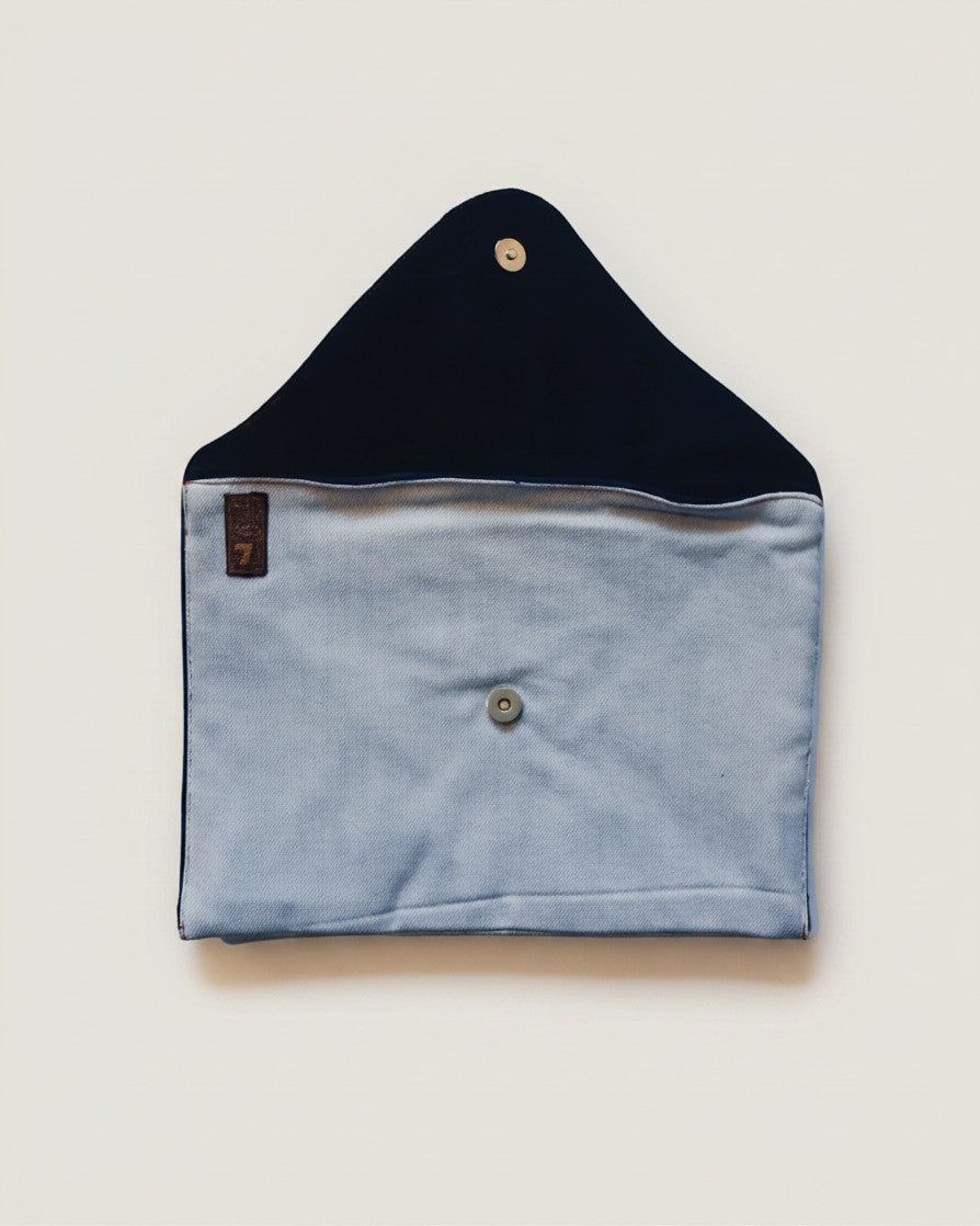 Hue Labs upcycled denim envelope clutch with a magnetic snap closure and interior pocket on a light background