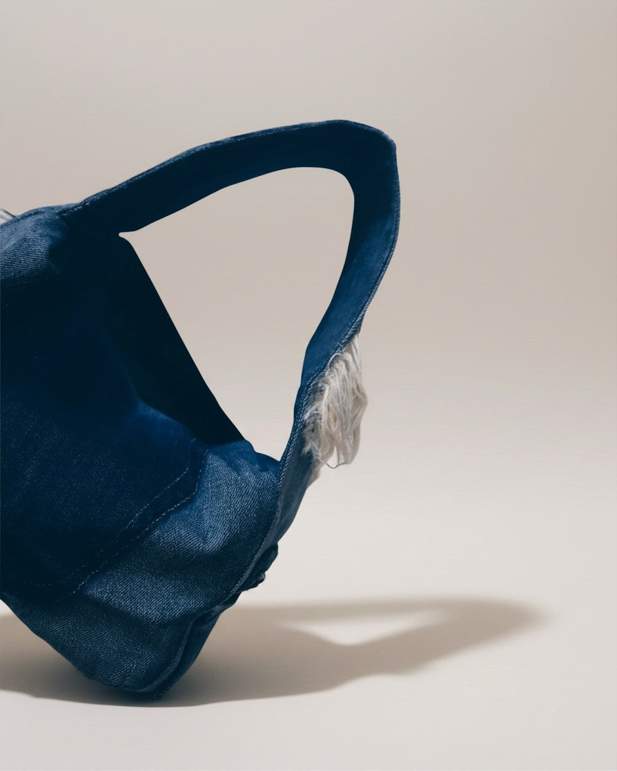 Hue Labs midnight blue distressed denim dumpling shoulder bag with a soft compact shape and frayed edge detail.