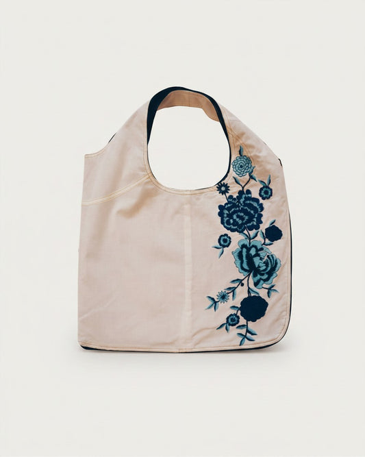 Hue Labs Floral Dreams reversible vest bag in cream fabric with blue floral embroidery and silver zipper details.