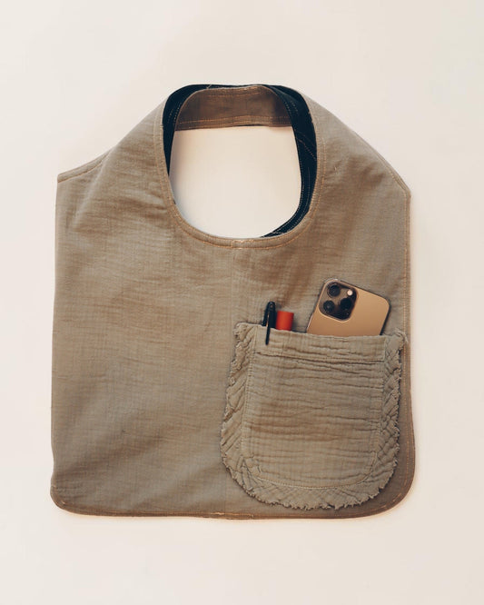 Hue Labs reversible Garden Vest Bag in sage green upcycled fabric with a front pocket holding a phone and pen.