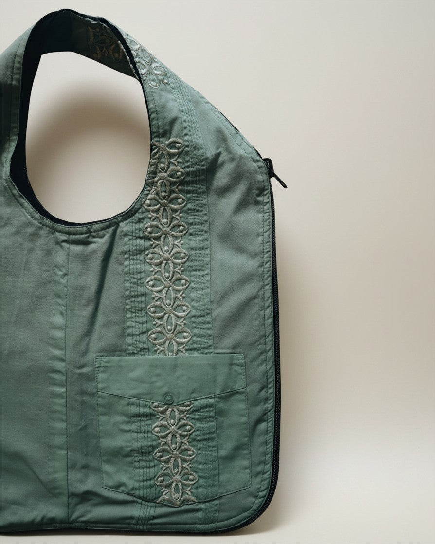 Hue Labs green floral upcycled vest bag with silver metal zipper and embroidered detailing on a neutral background.