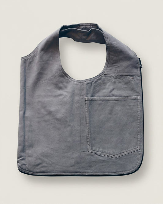 Hue Labs grey upcycled vest bag with a front pocket and gun metal zipper, designed as a reversible wearable accessory.