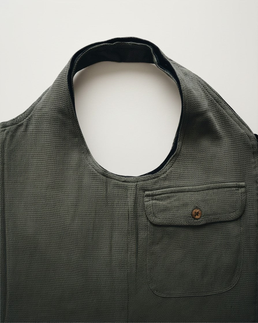 Hue Labs olive green upcycled vest bag with a textured fabric finish and a front patch pocket with a button closure.
