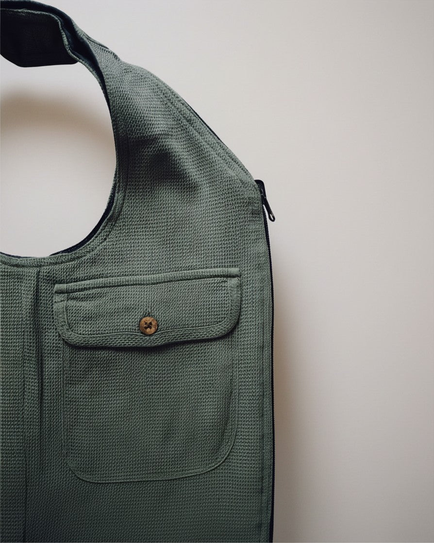 Hue Labs olive green upcycled vest bag with a textured waffle fabric, front pocket, and silver metal zipper detail.