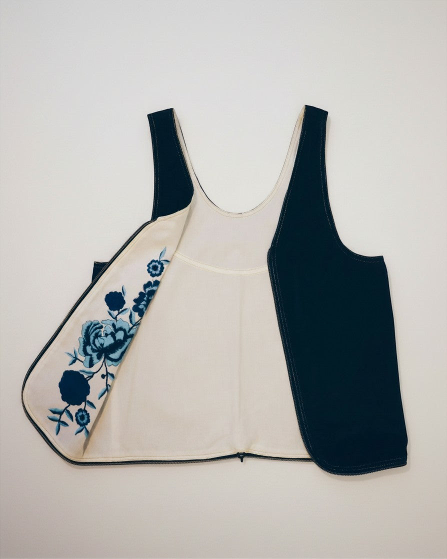 Hue Labs reversible vest bag in black and cream with blue floral embroidery, crafted from upcycled materials.