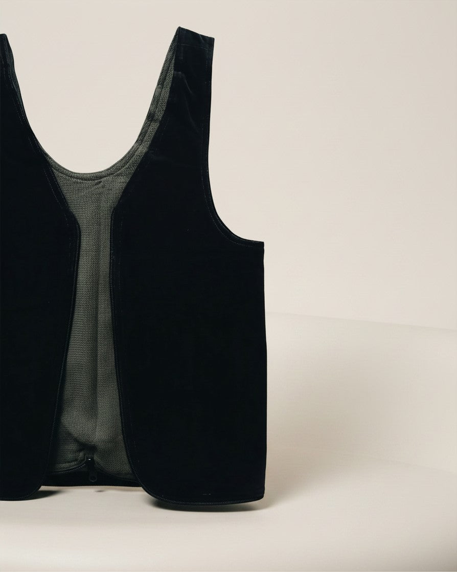 Hue Labs olive and black reversible upcycled vest bag with a silver metal zipper, shown in a studio setting.
