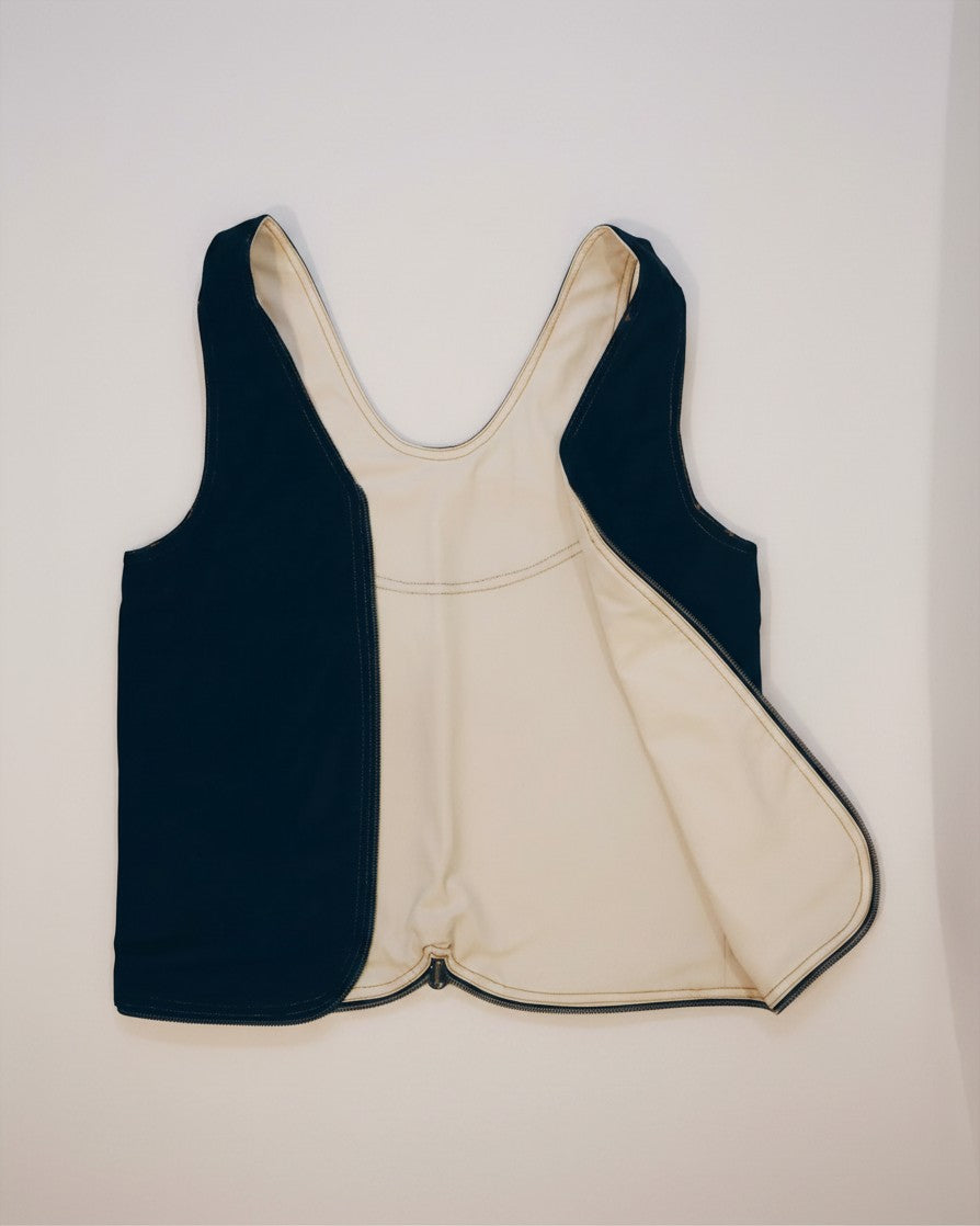 Hue Labs reversible white and black upcycled vest bag with a gun metal silver zipper, shown in a flat lay view.