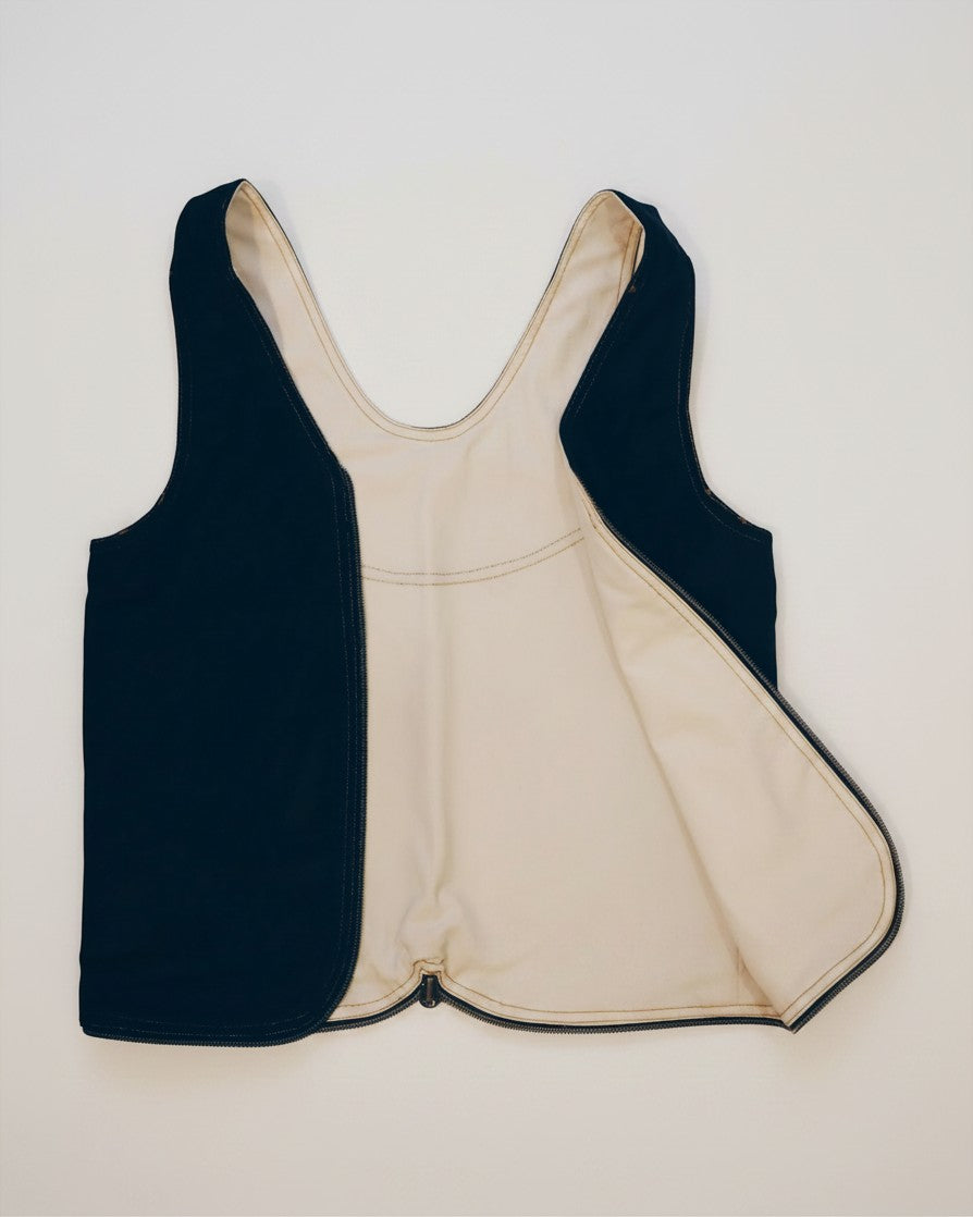 Hue Labs reversible vest bag in black and cream upcycled fabric with a silver metal zipper, shown partially open.