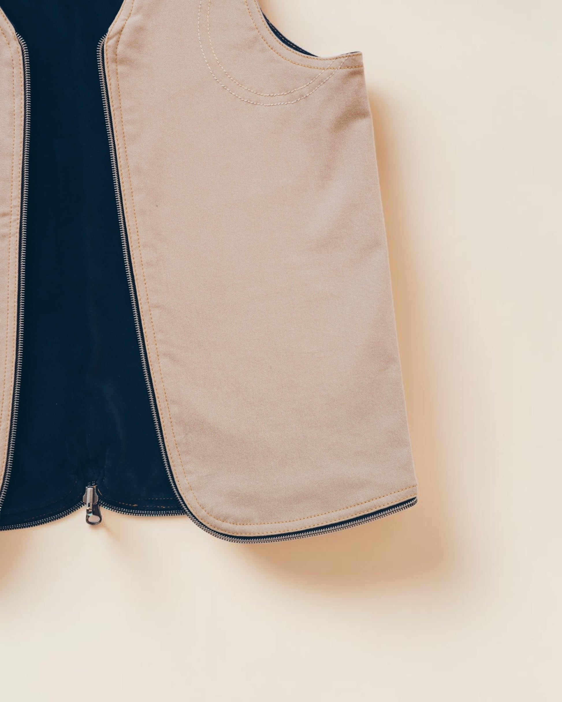 Hue Labs tan zip-up vest with dark navy interior lining and minimalist structured design.