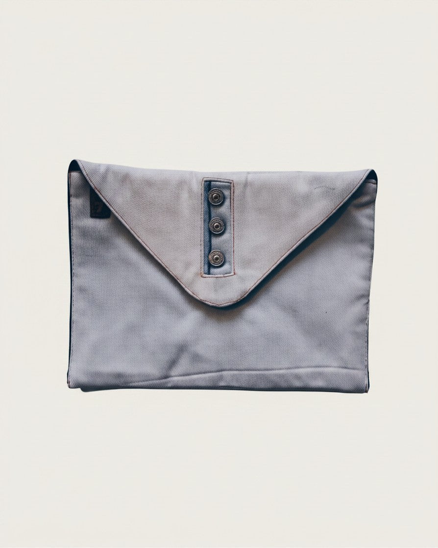 Hue Labs upcycled denim envelope clutch with a buttoned flap closure and magnetic snap in a light blue wash.
