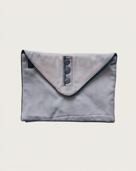 Hue Labs upcycled denim envelope clutch with a buttoned flap closure and magnetic snap in a light blue wash.